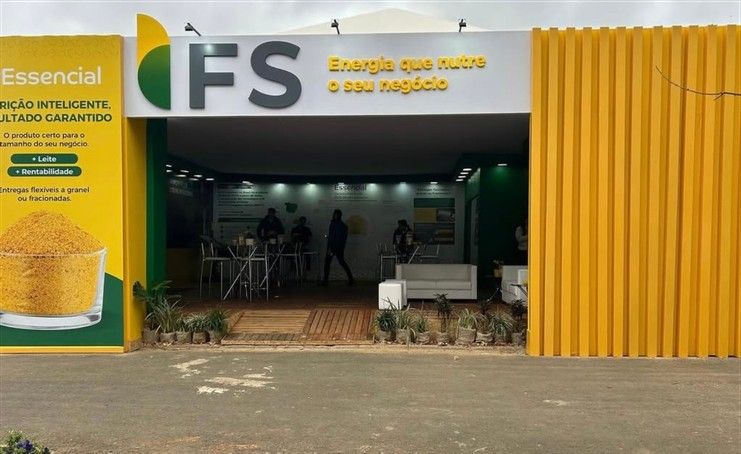 Estande FS Nutrição Animal em feira externa, com fachada ripada amarela e deck de madeira